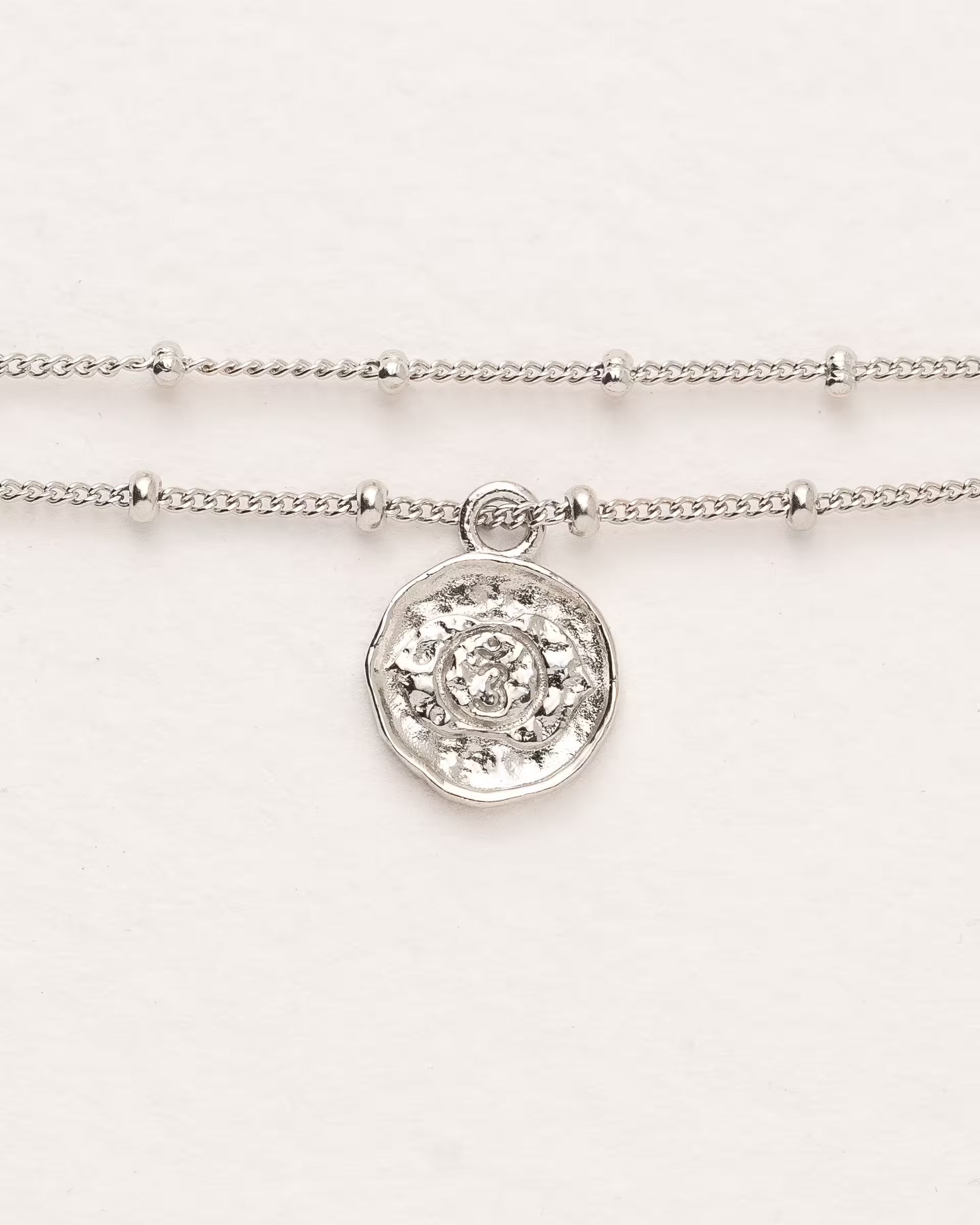 #Motiv_Ajna CHAKRA AJNA ARMBAND SILBER Produktbild – Dieses handgefertigte, silberne Armband mit einer feinen, doppelten Satellitenkette von ILUH aus Bali im minimalistischen Stil zeigt das originale Sanskrit-Zeichen für das Ajna-Stirnchakra; eingebettet in kunstvolle Lotusblütenblätter dient es als kraftvolles Symbol zur Stärkung deines Energiezentrums.
