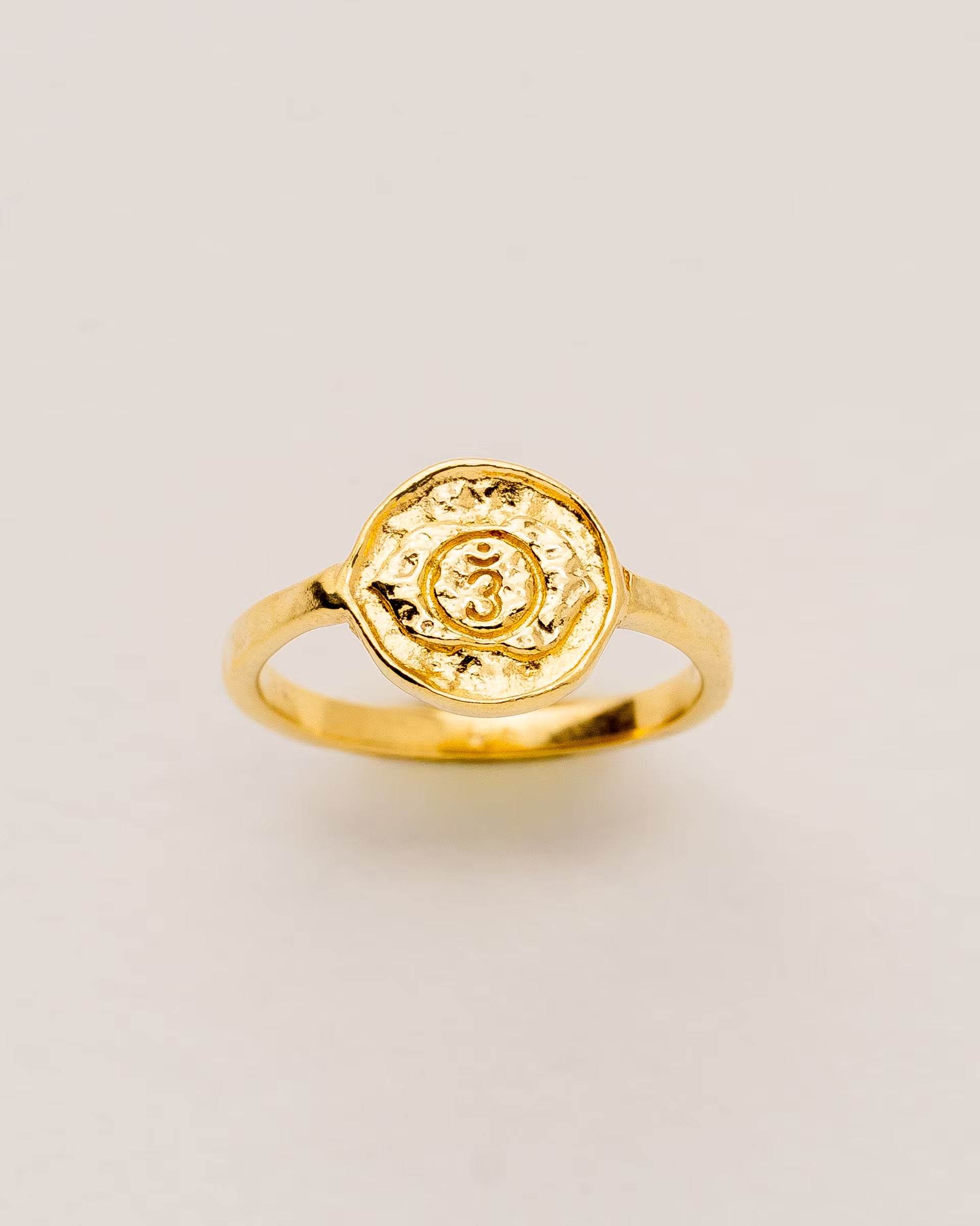 #Motiv_Ajna CHAKRA AJNA RING GOLD, goldener Siegelring von ILUH, handgefertigt auf Bali – Spirituelles Produktfoto im minimalistischen Boho-Look von einem Siegelring mit einer runden, strukturierten Platte, die das originale Sanskrit-Zeichen für das Ajna-Stirnchakra, eingebettet in kunstvolle Lotusblütenblätter zur Stärkung des Energiezentrums, zeigt.