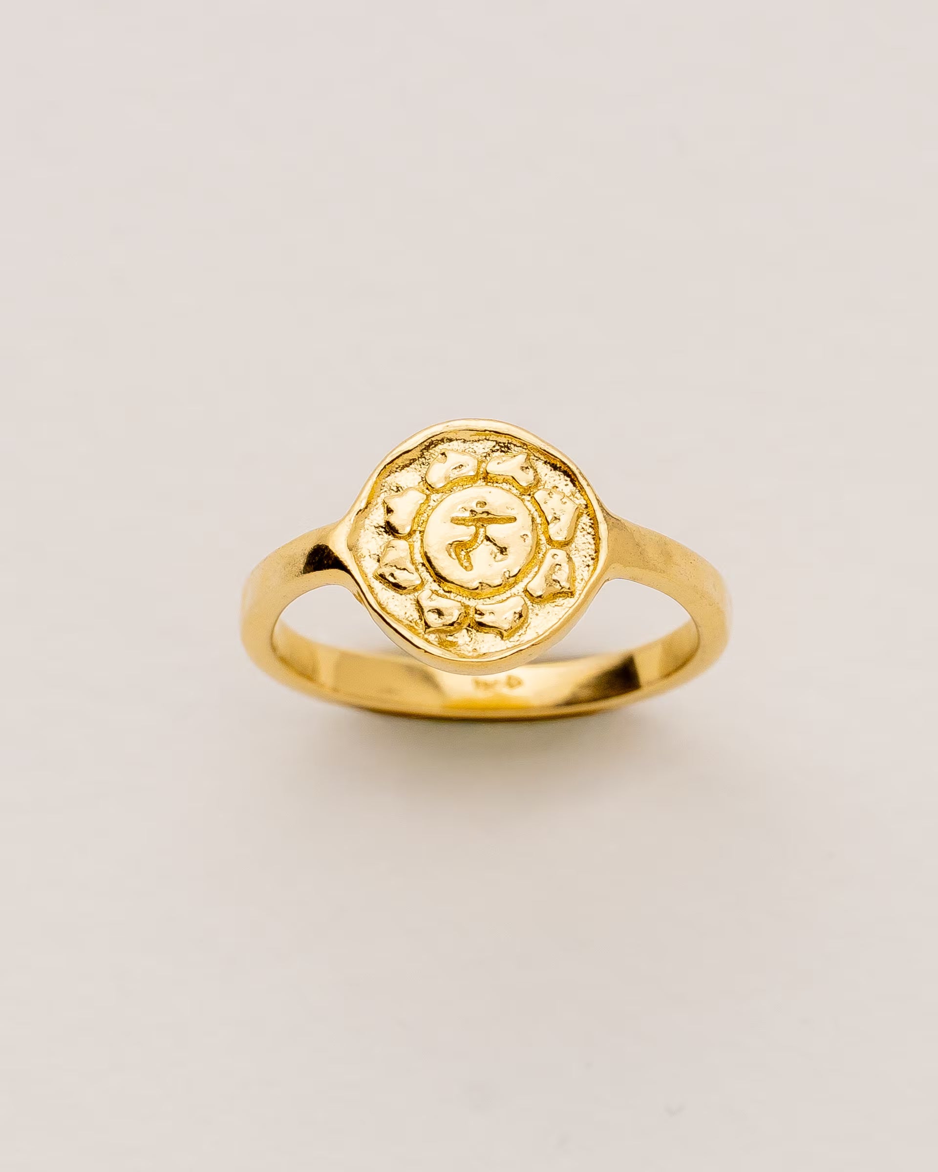 #Motiv_Manipura CHAKRA MANIPURA RING GOLD – Dieser handgefertigte Siegelring von ILUH aus Bali im minimalistischen Stil überzeugt durch eine runde, strukturierte Platte, die das originale Sanskrit-Zeichen für das Manipura-Solarplexuschakra zeigt; eingebettet in kunstvolle Lotusblütenblätter dient er als kraftvolles Symbol zur Stärkung deines Energiezentrums.
