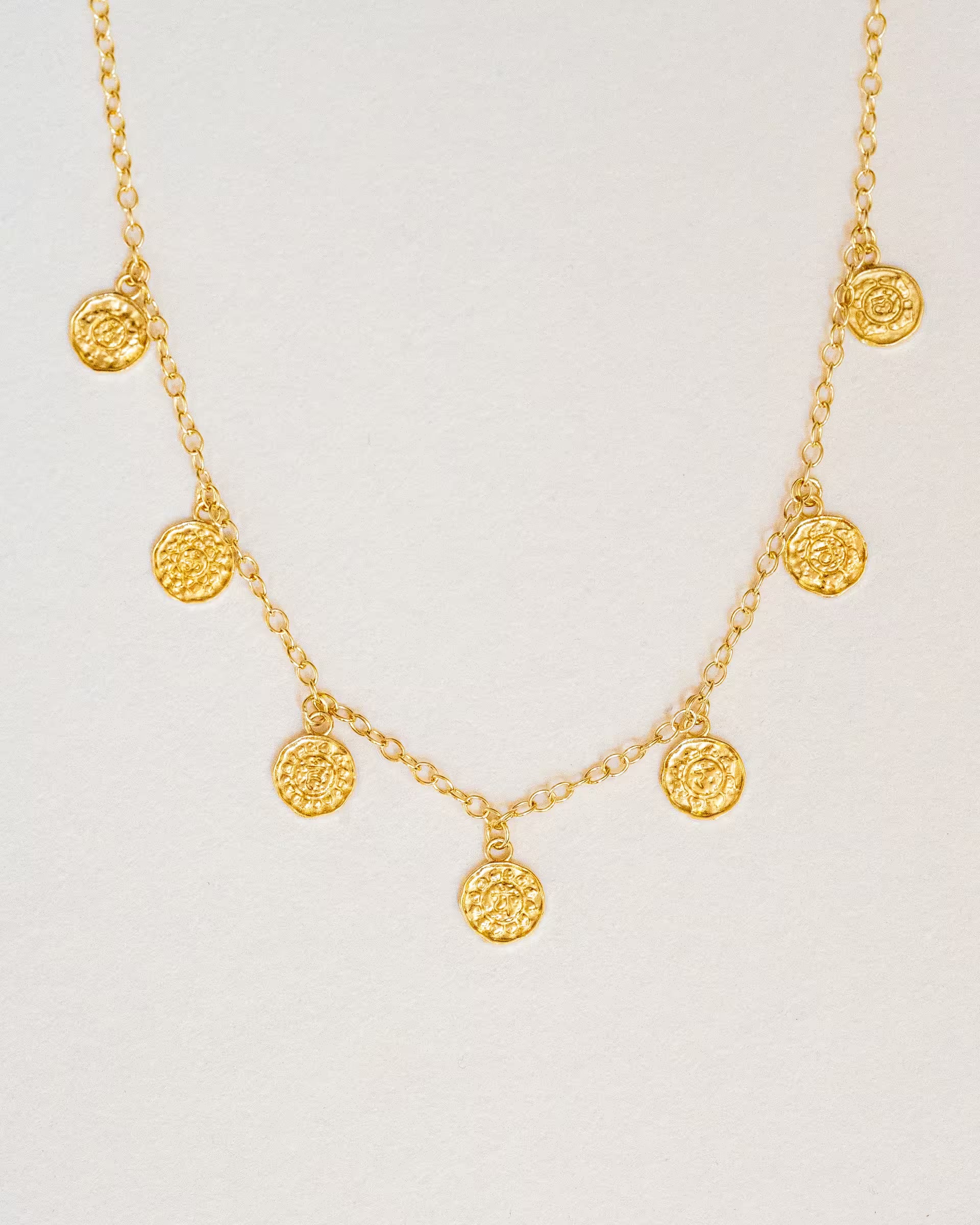 Goldene Prana-Halskette von ILUH mit sieben filigranen Anhängern; detaillierte Nahaufnahme des auf Bali handgefertigten Schmuckstücks, das den Fokus auf die feine Kettenstruktur und die hochwertige Gold-Optik legt.