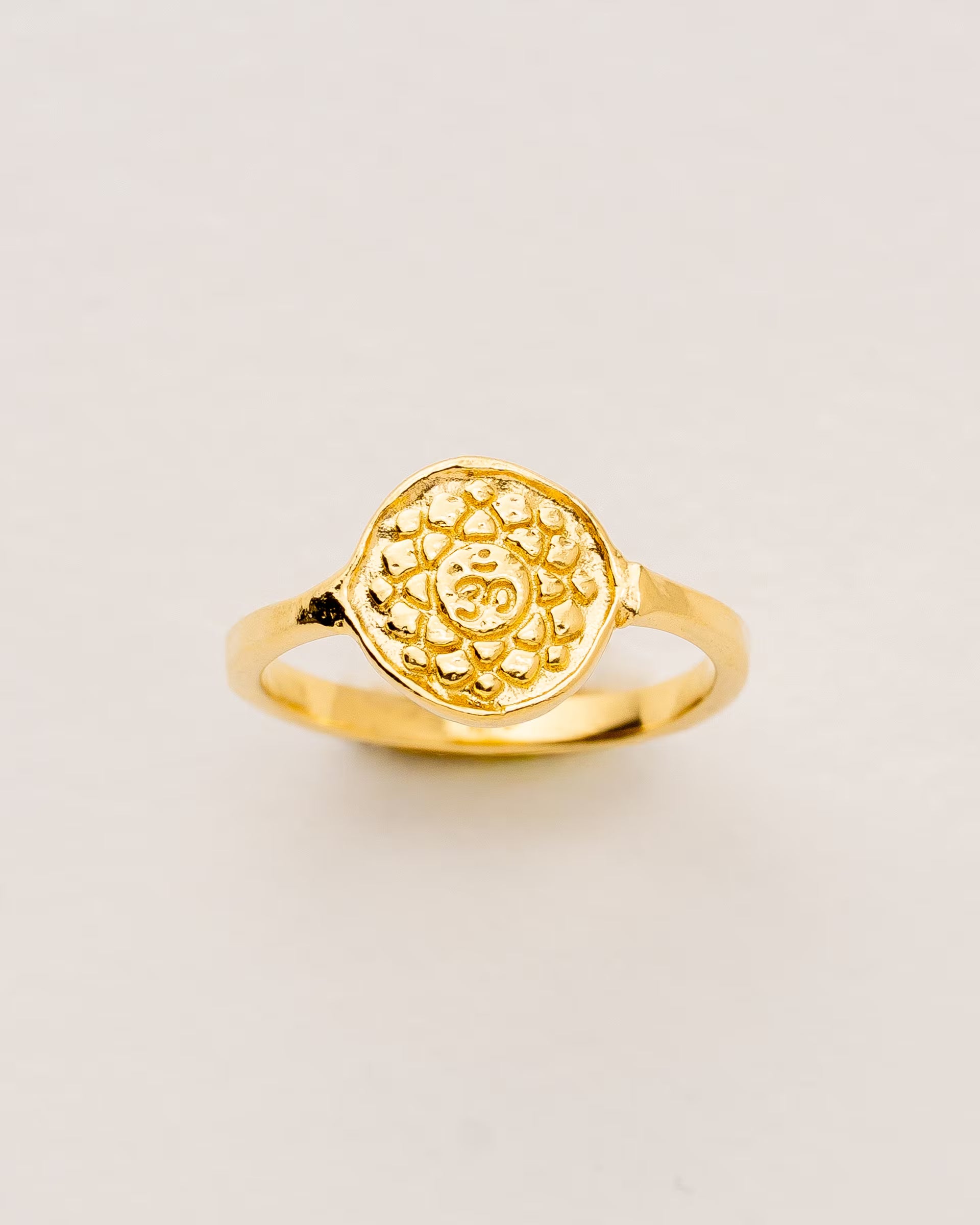 #Motiv_Sahasrara CHAKRA SAHASRARA RING GOLD – Dieser handgefertigte Siegelring von ILUH aus Bali im minimalistischen Stil überzeugt durch eine runde, strukturierte Platte, die das originale Sanskrit-Zeichen für das Sahasrara-Kronenchakra zeigt; eingebettet in kunstvolle Lotusblütenblätter dient er als kraftvolles Symbol zur Stärkung deines Energiezentrums.