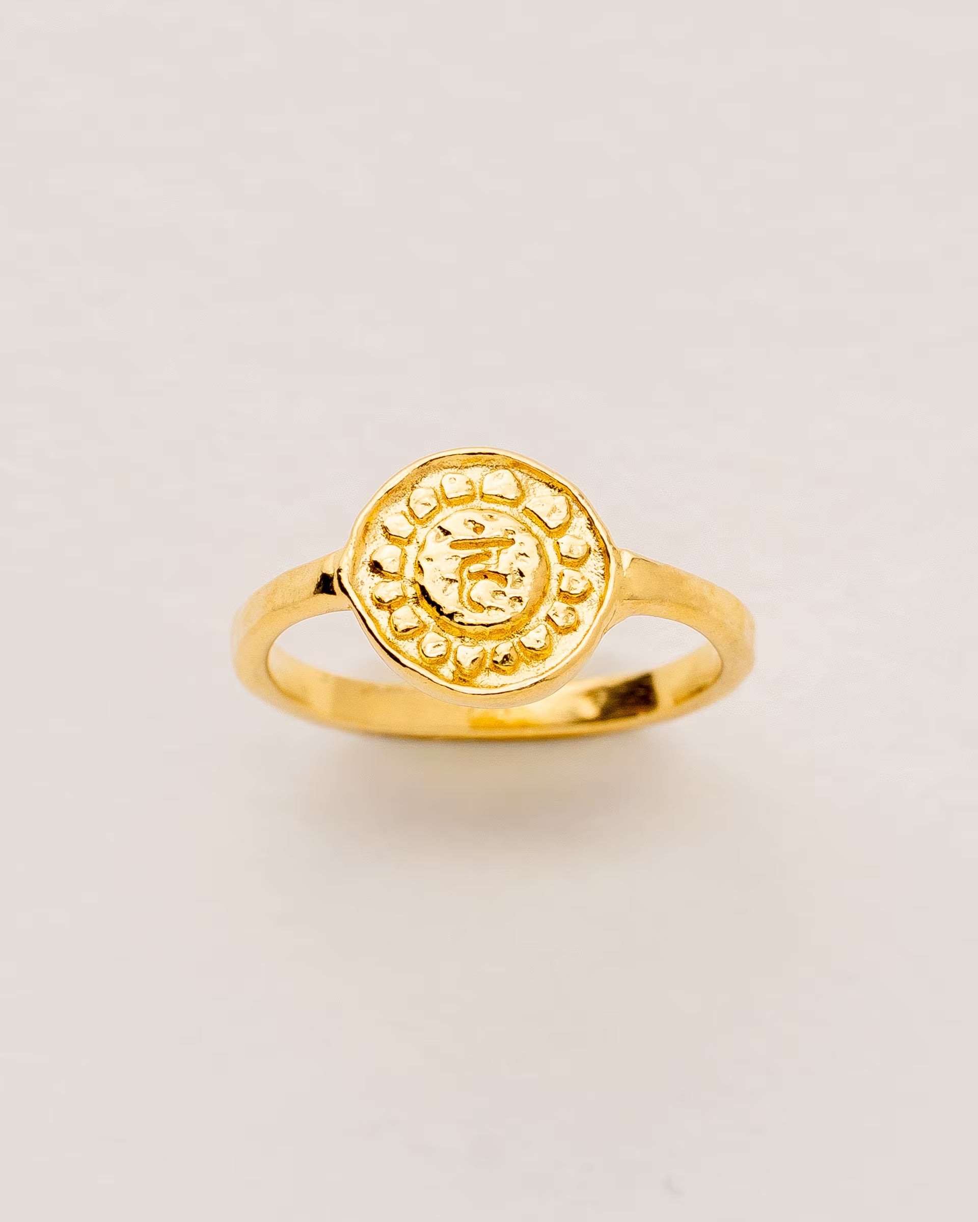 #Motiv_Vishuddha CHAKRA VISHUDDHA RING GOLD – Dieser handgefertigte Siegelring von ILUH aus Bali im minimalistischen Stil überzeugt durch eine runde, strukturierte Platte, die das originale Sanskrit-Zeichen für das Vishuddha-Halschakra zeigt; eingebettet in kunstvolle Lotusblütenblätter dient er als kraftvolles Symbol zur Stärkung deines Energiezentrums.