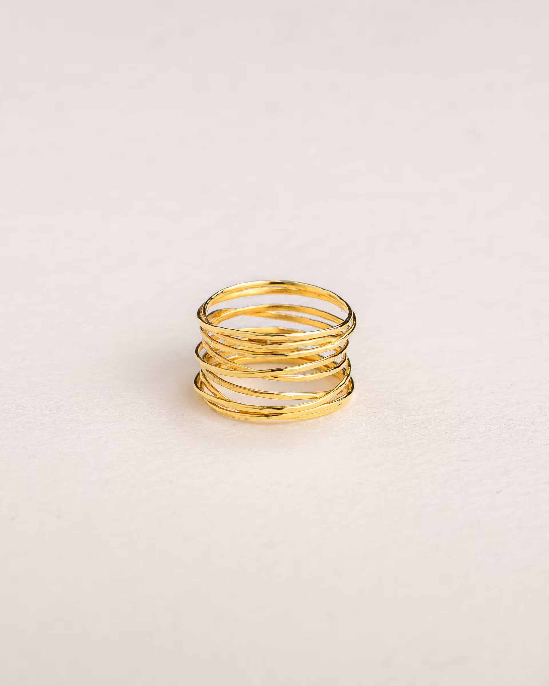 AURA RING GOLD Produktbild – Diese Nahaufnahme zeigt einen zarten Aura-Ring von der Schmuckmarke ILUH aus Bali in einem cleanen Design; das Schmuckstück besticht durch seinen kunstvoll gewickelten Silberfaden in einem eleganten Wickeldesign mit gehämmerter Struktur, hergestellt aus 925 Sterlingsilber und mit 18k vergoldet.