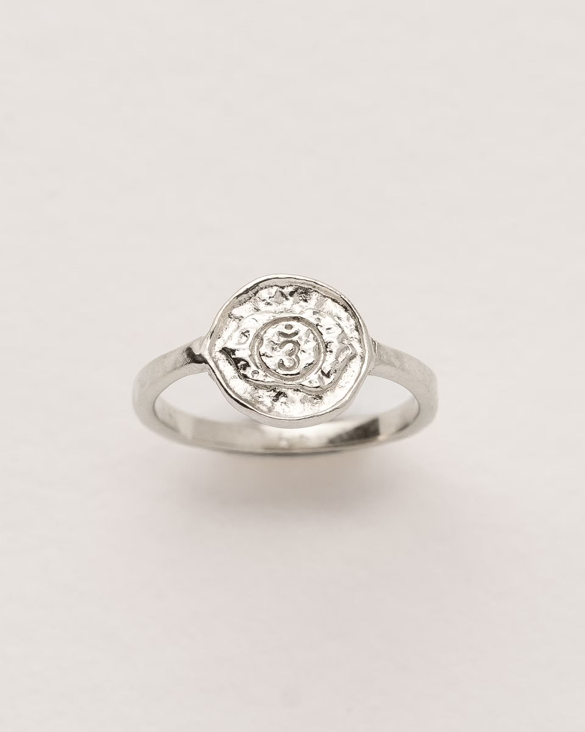 #Motiv_Ajna CHAKRA AJNA RING SILBER, silberner Siegelring von ILUH, handgefertigt auf Bali – Spirituelles Produktfoto im minimalistischen Look von einem Siegelring mit einer runden, strukturierten Platte, die das originale Sanskrit-Zeichen für das Ajna-Stirnchakra zeigt; eingebettet in kunstvolle Lotusblütenblätter dient er als Symbol zur Stärkung deines Energiezentrums.