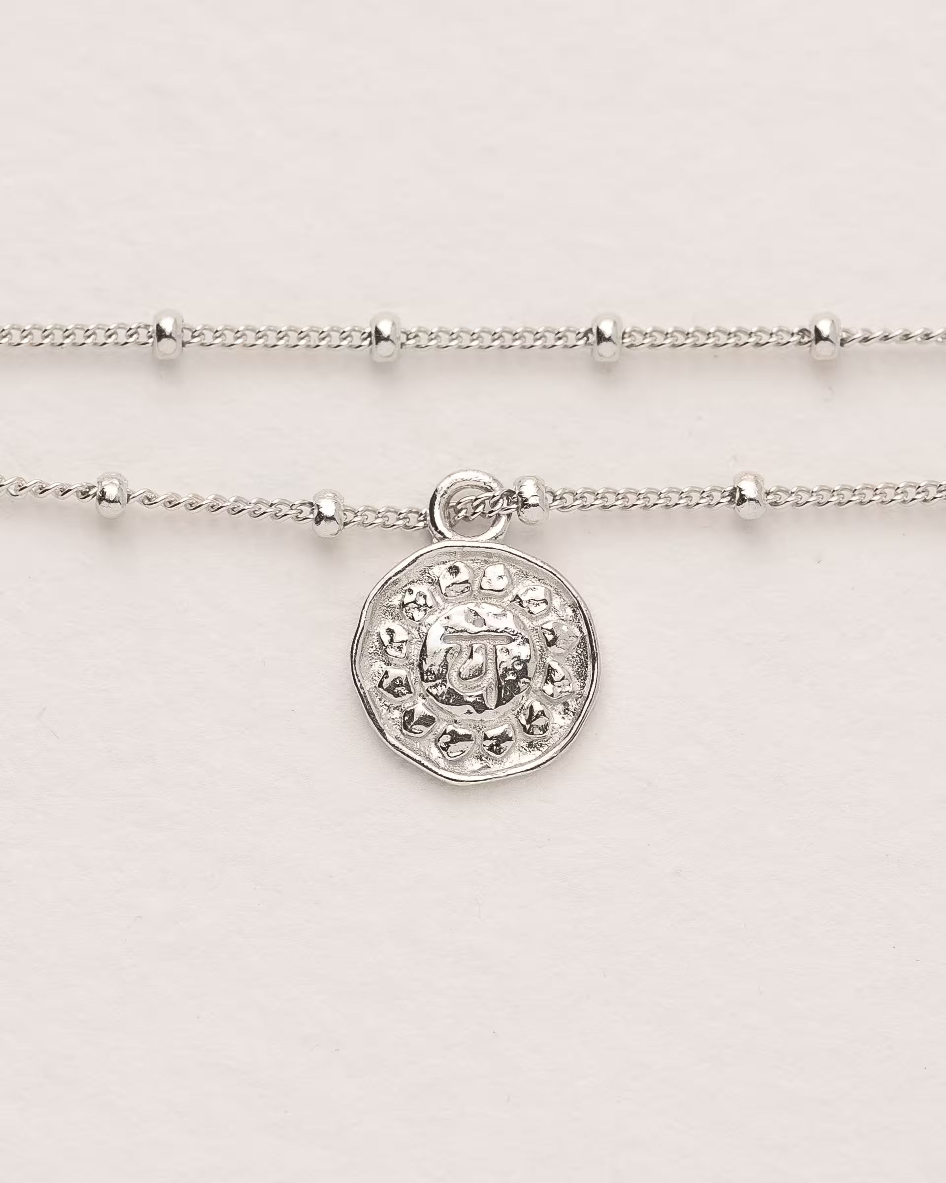 #Motiv_Anahata CHAKRA ANAHATA ARMBAND SILBER – Dieses handgefertigte, silberne Armband mit einer feinen, doppelten Satellitenkette von der Schmuckmarke ILUH aus Bali im minimalistischen Stil zeigt das originale Sanskrit-Zeichen für das Anahata-Herzchakra; eingebettet in kunstvolle Lotusblütenblätter dient es als kraftvolles Symbol zur Stärkung deines Energiezentrums.