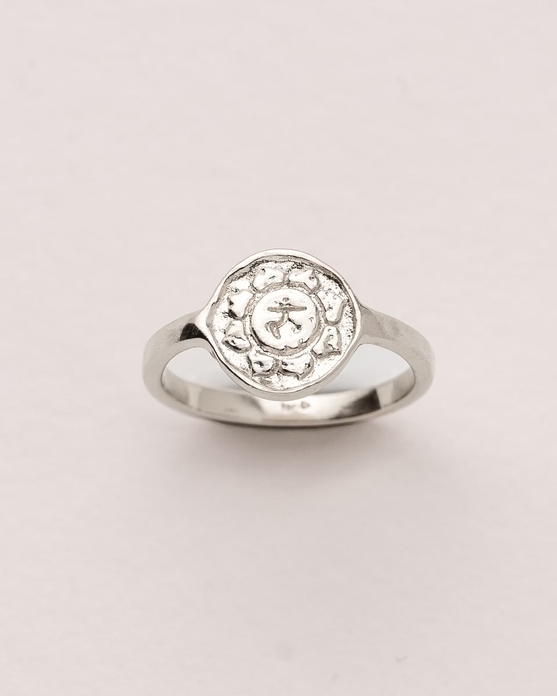 #Motiv_Manipura CHAKRA MANIPURA RING SILBER  – Dieser handgefertigte Siegelring von ILUH aus Bali im minimalistischen Stil überzeugt durch eine runde, strukturierte Platte, die das originale Sanskrit-Zeichen für das Manipura-Solarplexuschakra zeigt; eingebettet in kunstvolle Lotusblütenblätter dient er als kraftvolles Symbol zur Stärkung deines Energiezentrums.