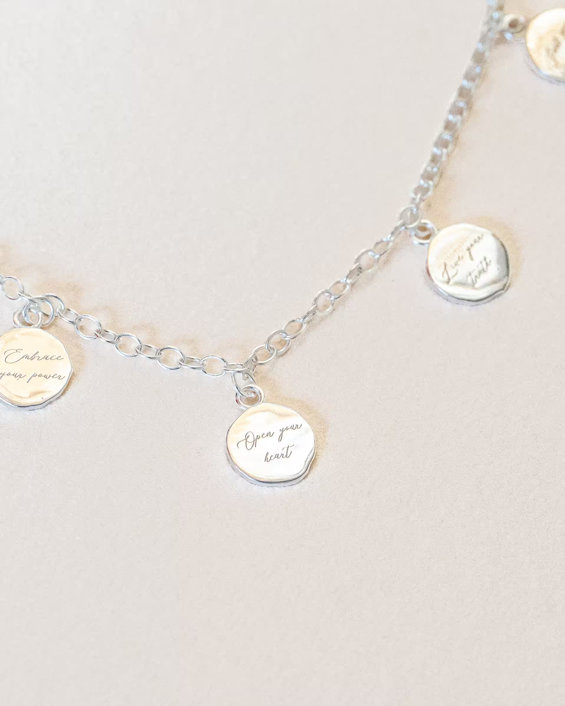 Detailaufnahme der silbernen Prana-Halskette von ILUH aus recyceltem 925 Sterling Silber, die filigrane Gravuren wie 'Open your heart' und 'Embrace your power' als spirituellen Schmuck zeigt, handgefertigt auf Bali.