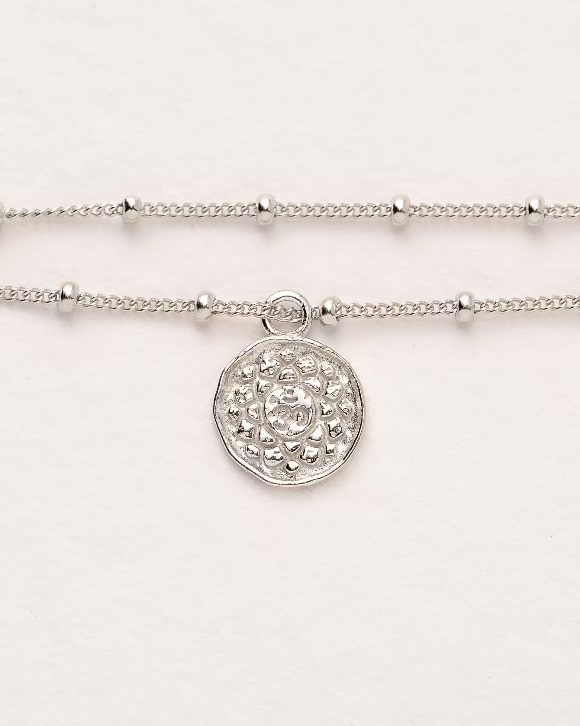 #Motiv_Sahasrara CHAKRA SAHASRARA ARMBAND SILBER Produktbild – Dieses handgefertigte, silberne Satellitenarmband von der Schmuckmarke ILUH aus Bali im minimalistischen Stil zeigt das originale Sanskrit-Zeichen für das Sahasrara-Kronenchakra; eingebettet in kunstvolle Lotusblütenblätter dient es als kraftvolles Symbol zur Stärkung deines Energiezentrums.