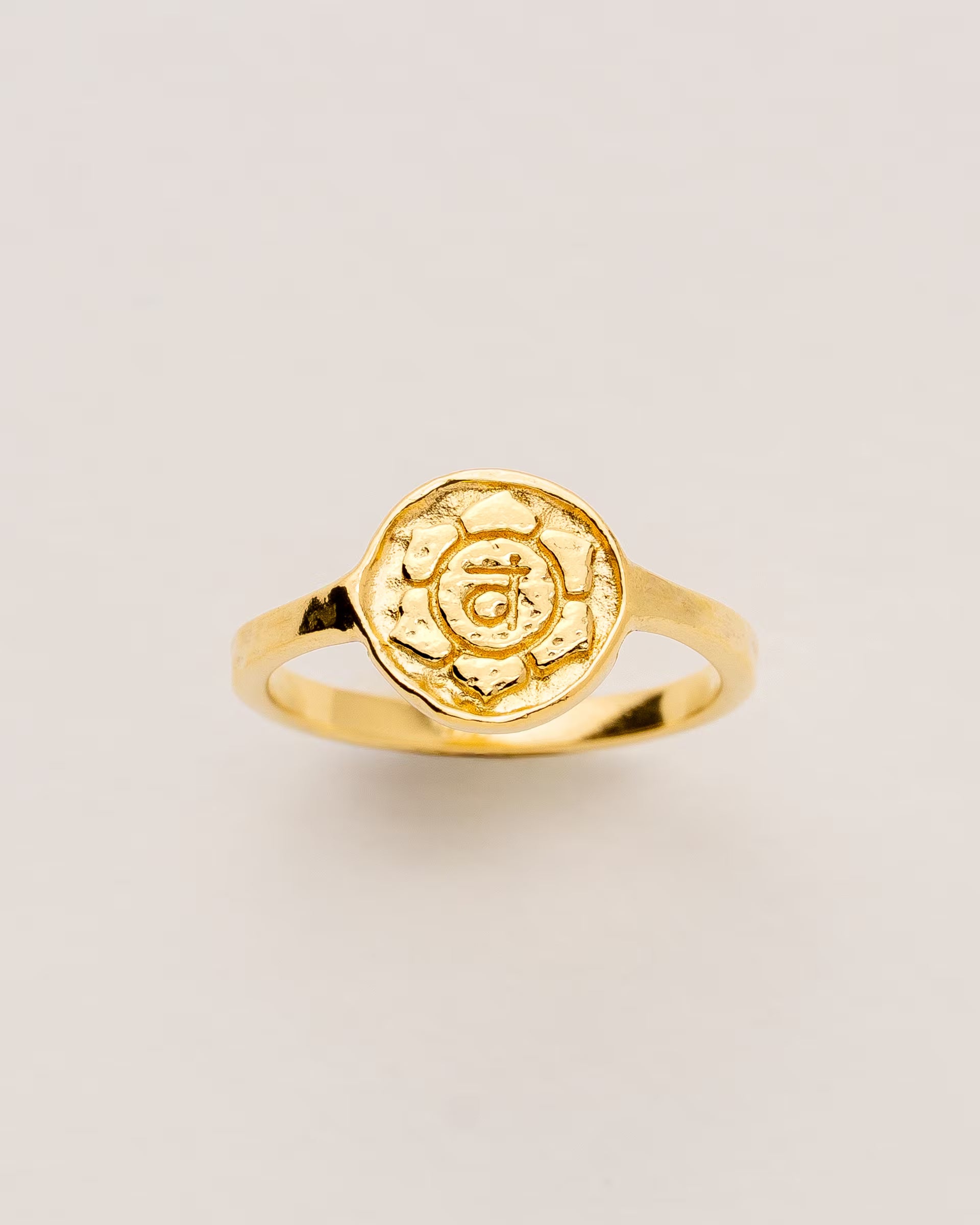 #Motiv_Svadhisthana CHAKRA SVADHISTHANA RING GOLD – Dieser handgefertigte Siegelring von ILUH aus Bali im minimalistischen Stil überzeugt durch eine runde, strukturierte Platte, die das originale Sanskrit-Zeichen für das Svadhisthana-Sakralchakra zeigt; eingebettet in kunstvolle Lotusblütenblätter dient er als kraftvolles Symbol zur Stärkung deines Energiezentrums.