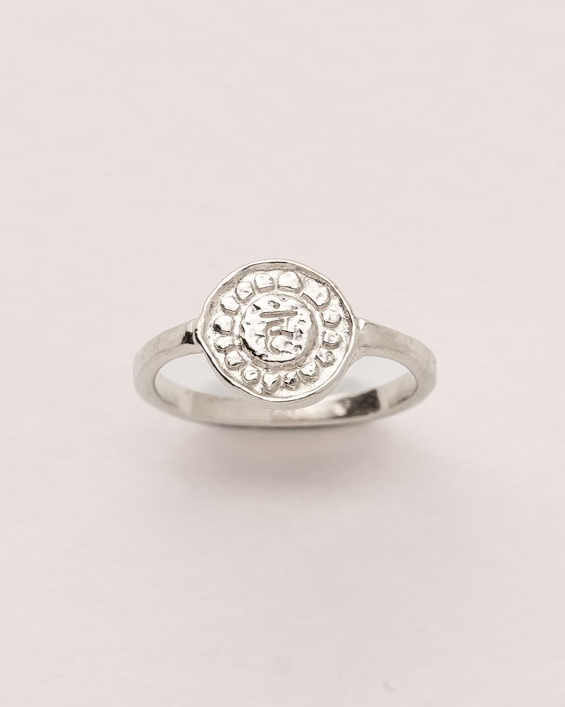 #Motiv_Vishuddha CHAKRA VISHUDDHA RING SILBER, silberner Siegelring von ILUH, handgefertigt auf Bali – Spirituelles Produktfoto im minimalistischen Look von einem Siegelring mit einer runden, strukturierten Platte, die das originale Sanskrit-Zeichen für das Vishuddha-Halschakra, eingebettet in kunstvolle Lotusblütenblätter zur Stärkung des Energiezentrums, zeigt.