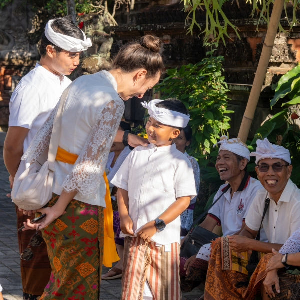 Timea, Gründerin des Schmuck-Labels ILUH, im herzlichen Austausch mit balinesischen Einheimischen in traditioneller Kleidung; das Bild steht für die enge familiäre Verbundenheit, transparente Handarbeit und faire Produktionsbedingungen auf Bali.